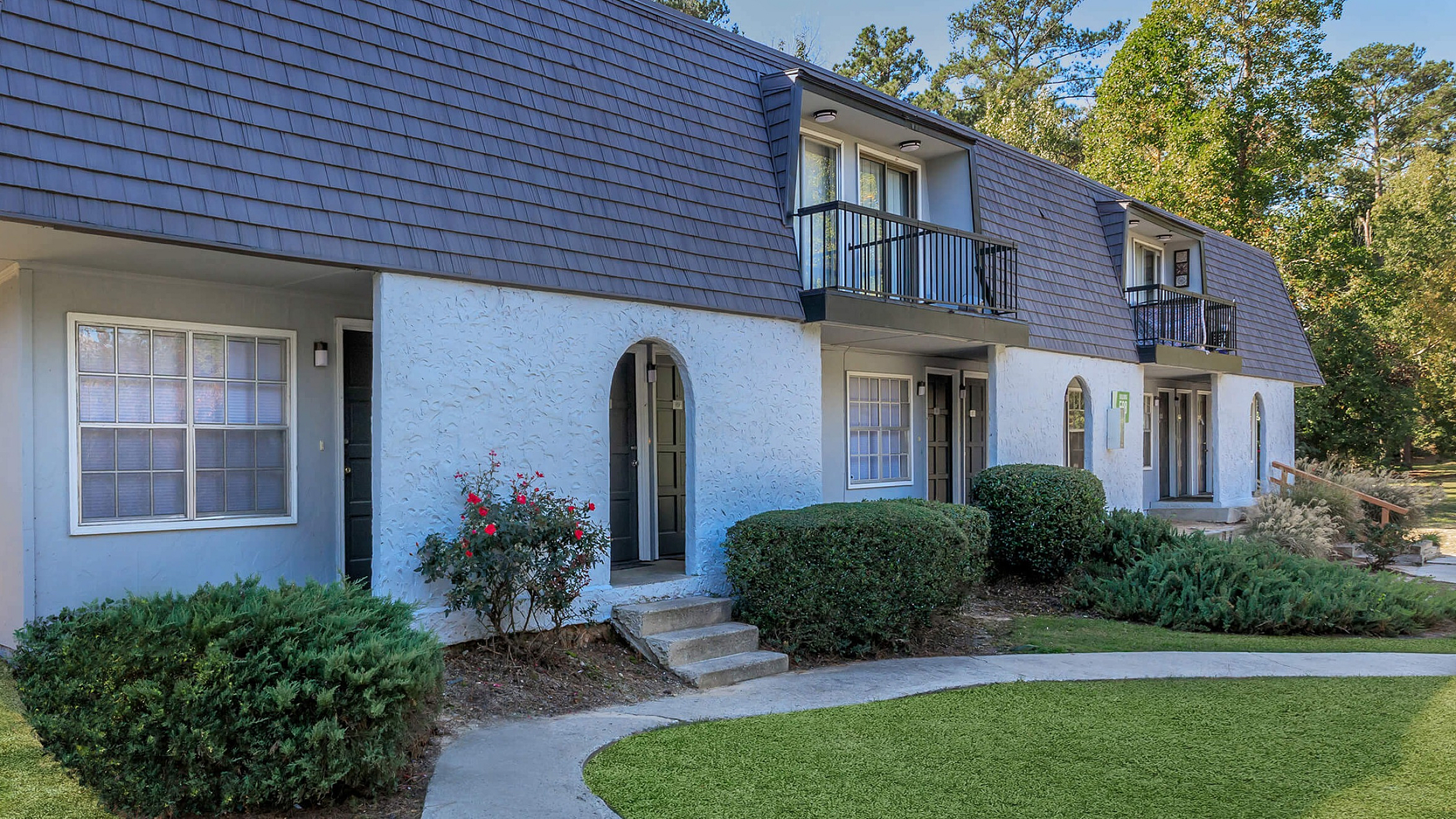 Front view of a charming apartment building with well-maintained landscaping and quaint balconies.