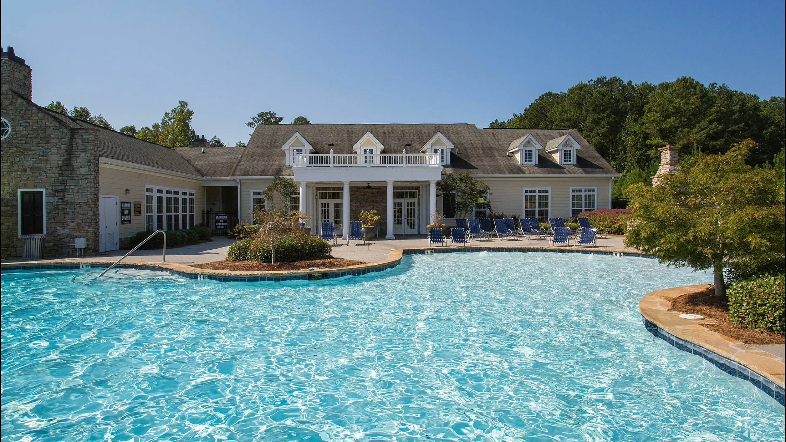 Elegant pool area in front of a charming residential building with a classic architectural design.