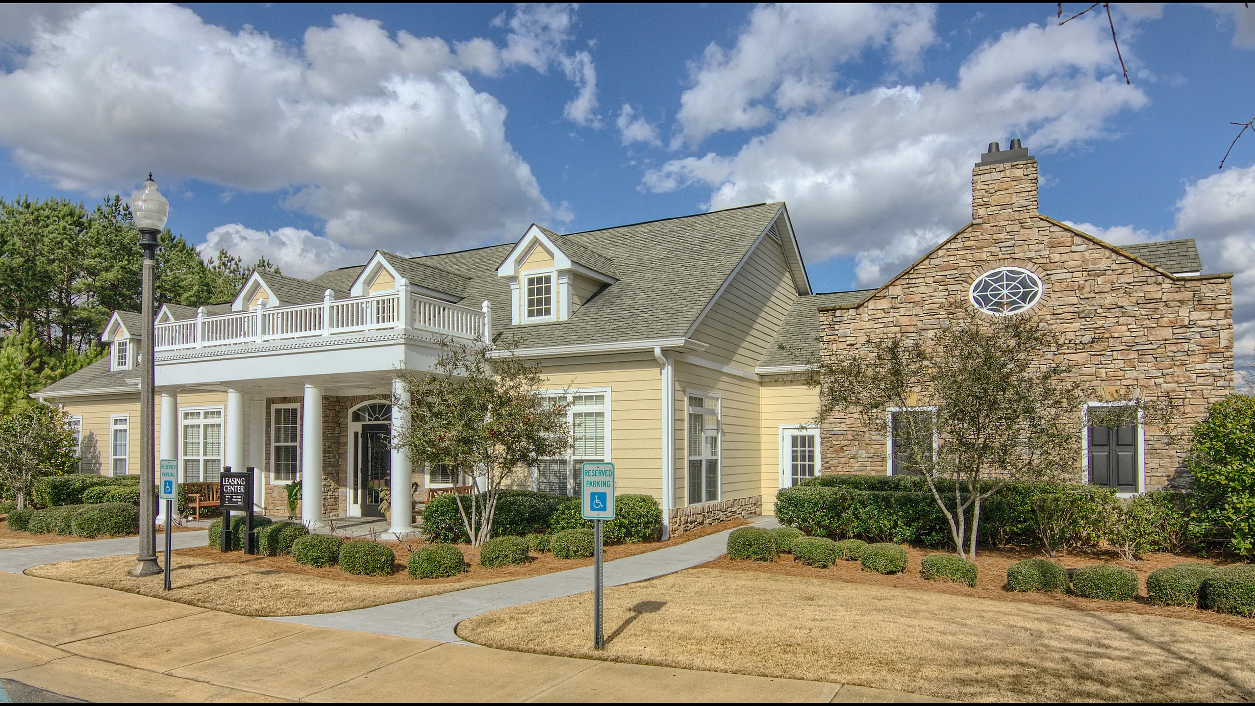 Charming leasing office with stone and siding facade under a bright blue sky with lush landscaping.