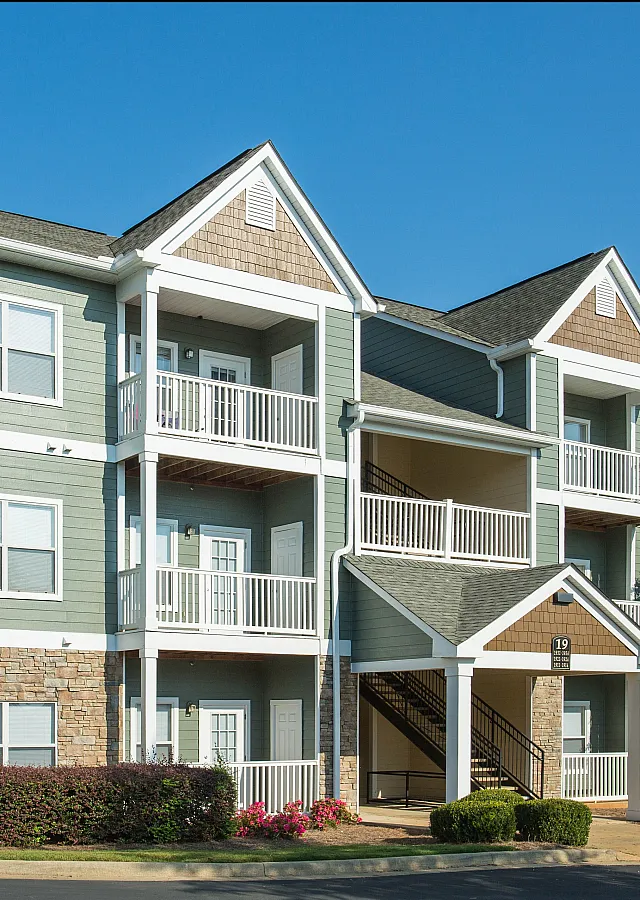 Charming three-story apartment building with balconies and lush landscaping.
