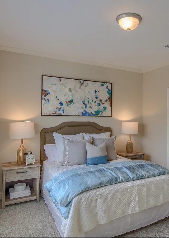 Inviting bedroom interior with plush bedding, soft lighting, and abstract artwork.
