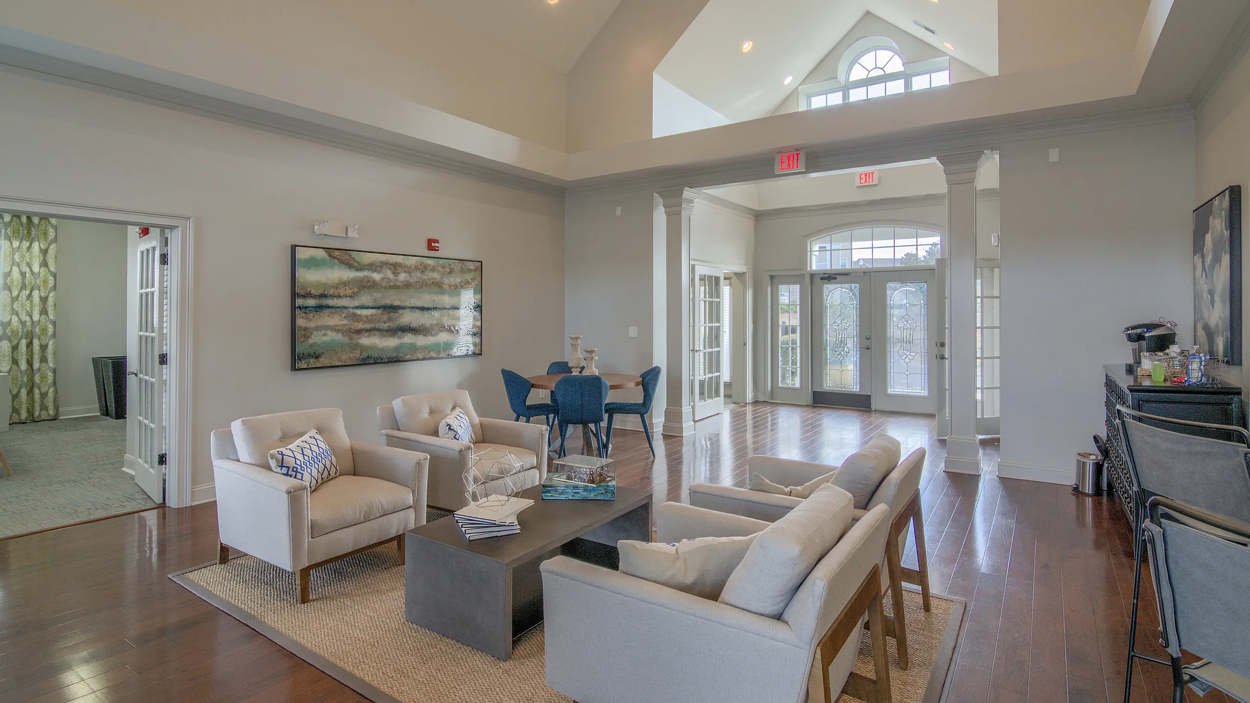 Spacious living room with vaulted ceiling, modern furniture, and natural light from large windows.