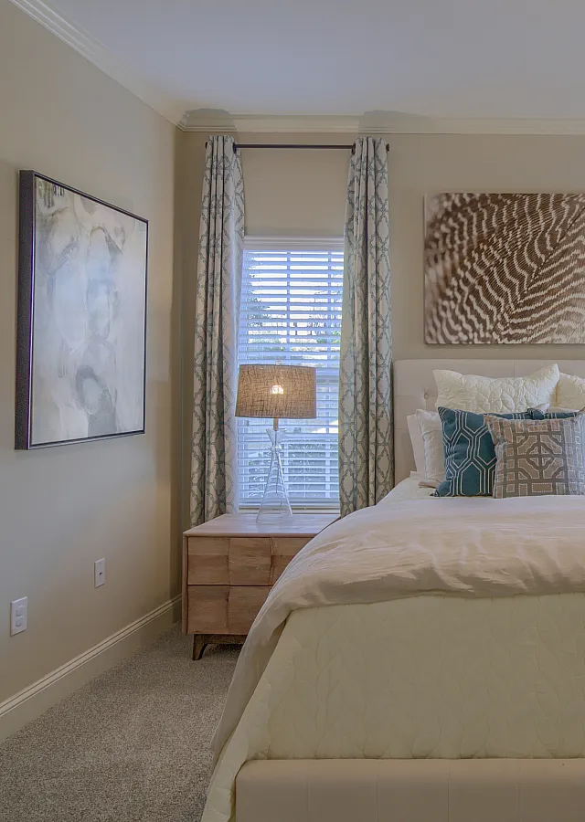 Bright and cozy bedroom with stylish decor, featuring soft lighting, patterned drapes, and an inviting bed.