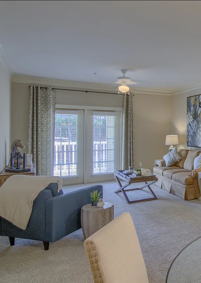 Bright and modern living room with stylish furniture, warm lighting, and a view of a private balcony.
