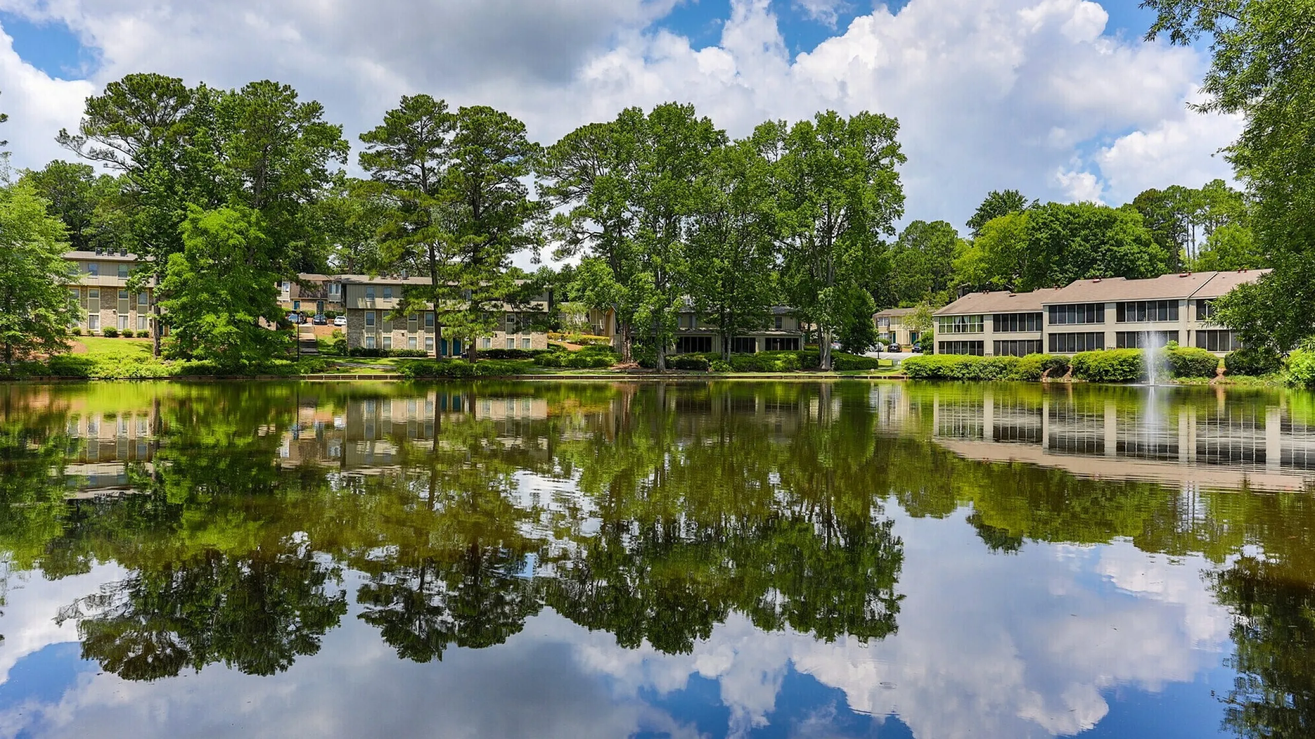 Serene apartment complex surrounded by lush greenery and a tranquil lake, perfect for nature lovers seeking a peaceful lifestyle.