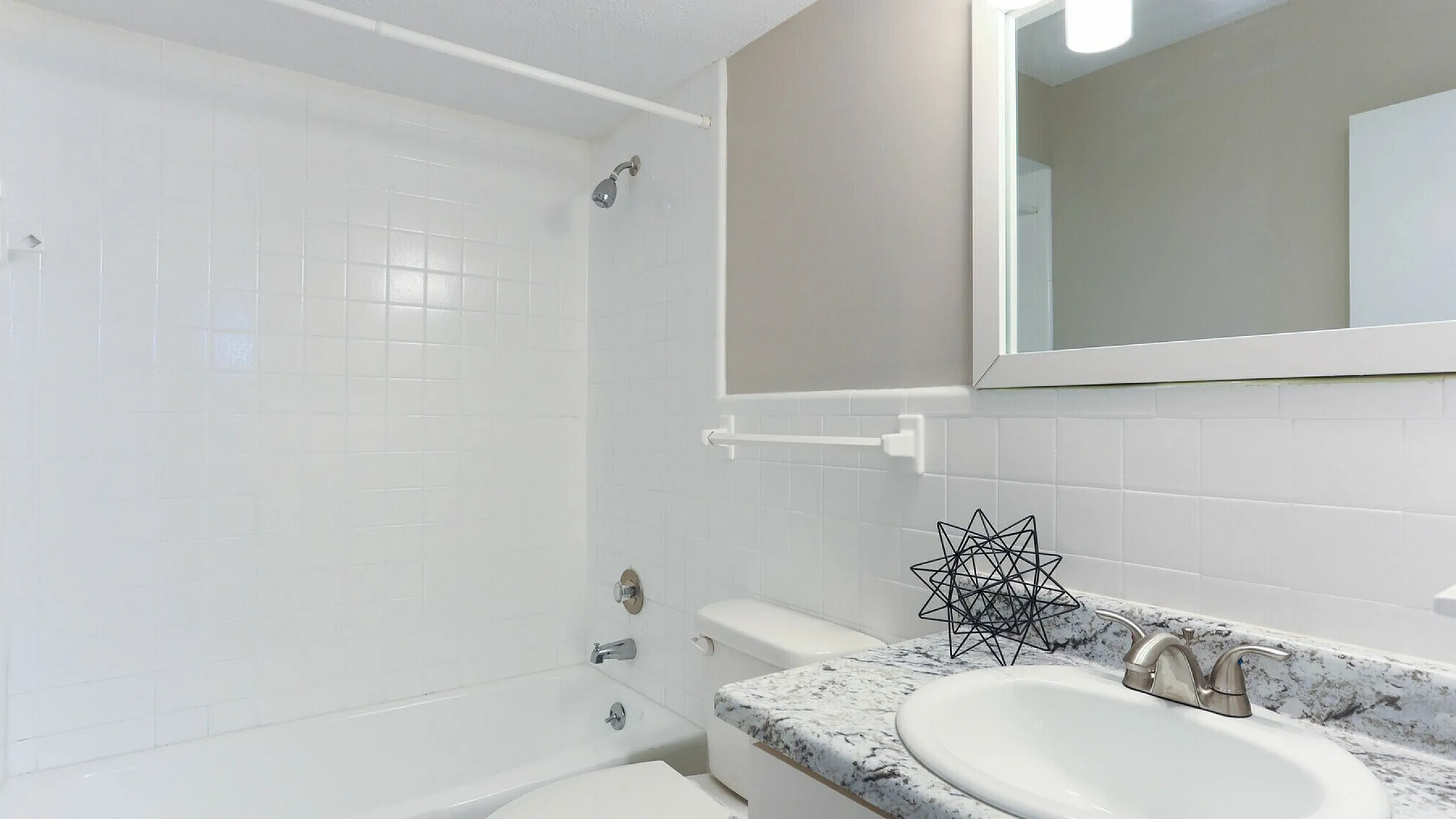 Elegant bathroom featuring a sleek granite countertop, modern fixtures, and a pristine bathtub, ideal for relaxation.
