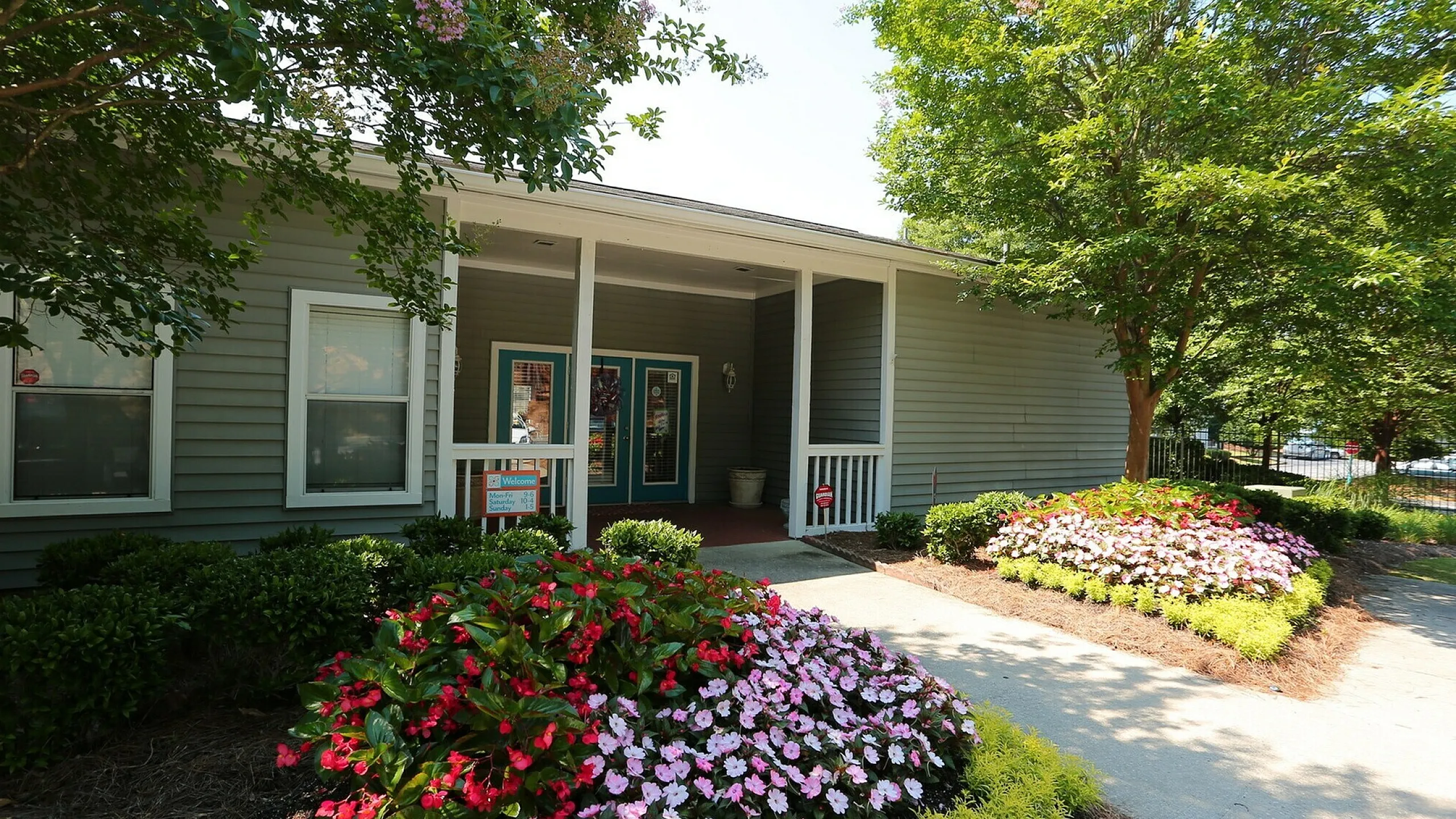 Charming apartment entrance surrounded by vibrant flower beds and lush greenery, offering a serene welcome.
