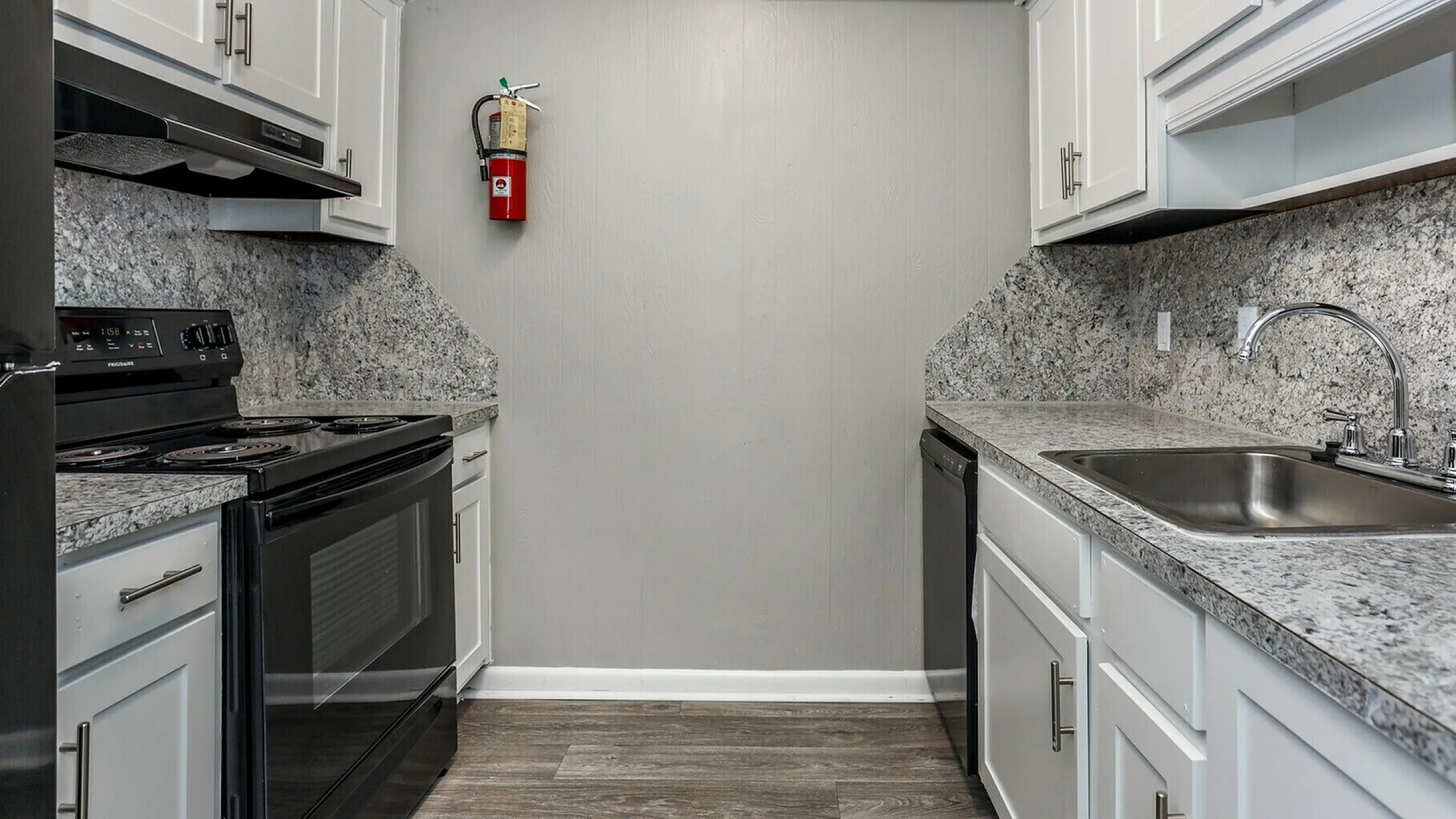 Modern kitchen with sleek granite countertops, stainless steel sink, and stylish white cabinetry.