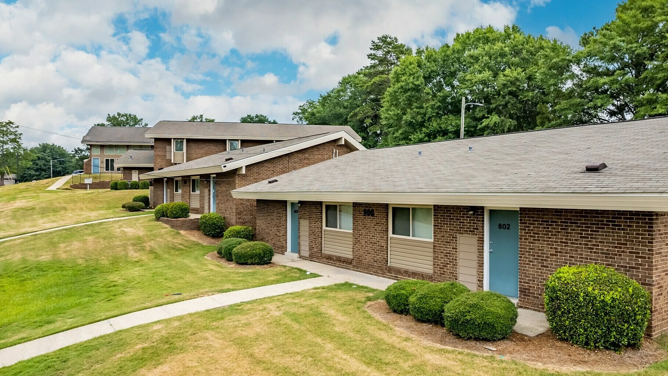 Charming apartment homes with a lush green landscape, featuring a modern exterior and inviting pathways.
