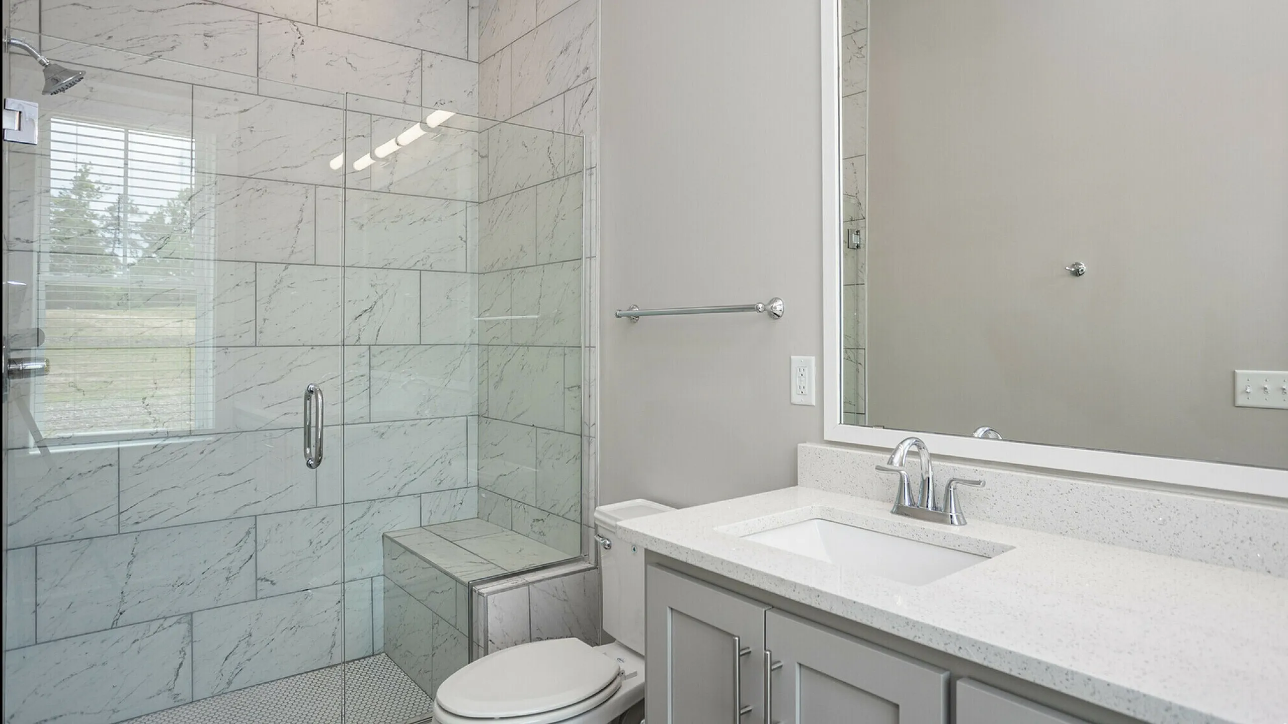 Modern bathroom with elegant marble tile shower, sleek vanity, and bright natural light.