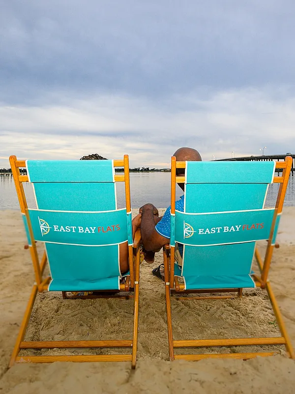 Relaxing beachfront view with two vibrant East Bay Flats chairs facing a serene ocean backdrop, perfect for a peaceful retreat.