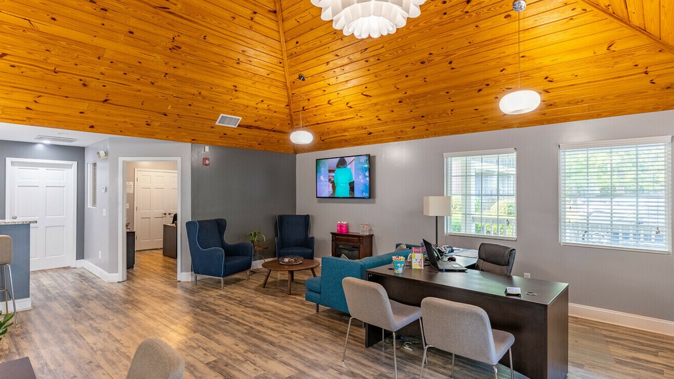 Inviting office space with warm wooden ceiling, comfortable seating, and natural light from large windows.