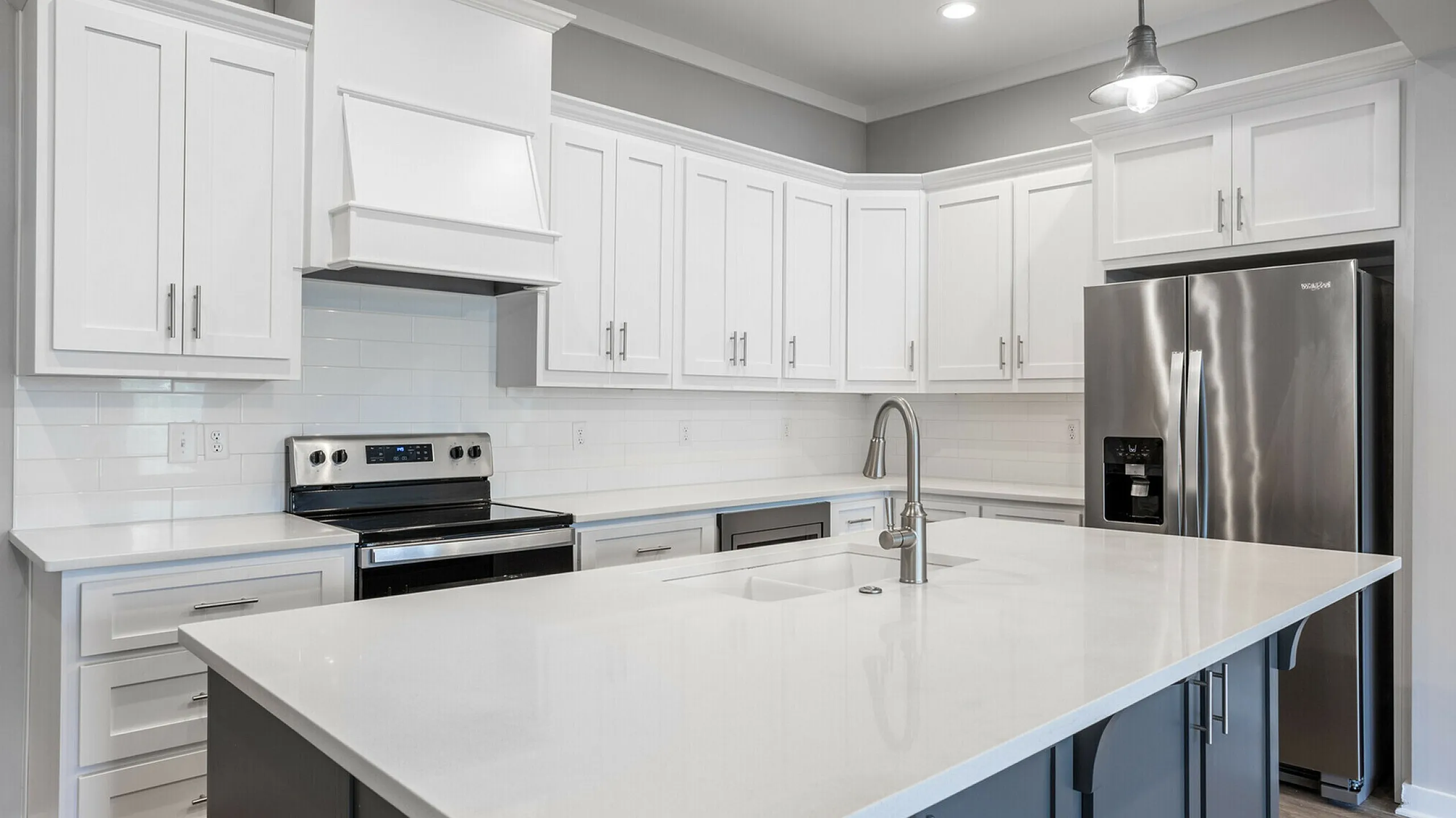 Sleek modern kitchen featuring elegant white cabinetry, stainless steel appliances, and a spacious island with a chic faucet.