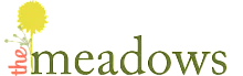 Elegant logo for 'The Meadows' featuring a vibrant yellow flower symbolizing growth and freshness.