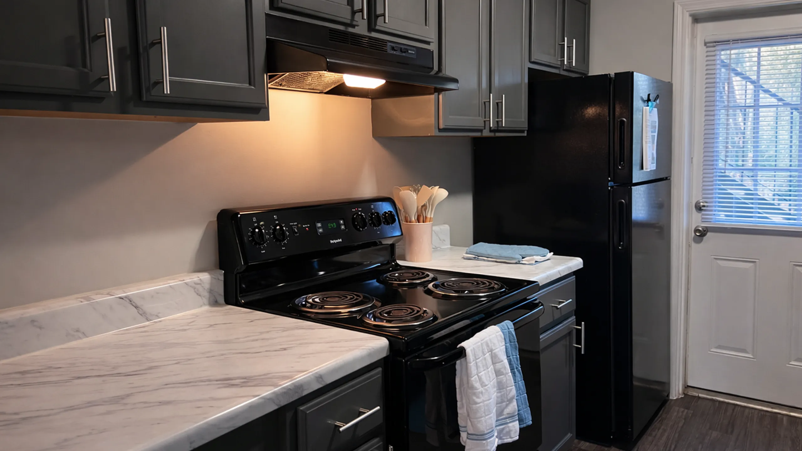 Modern kitchen with sleek black appliances and elegant marble countertops, offering a cozy and functional cooking space.