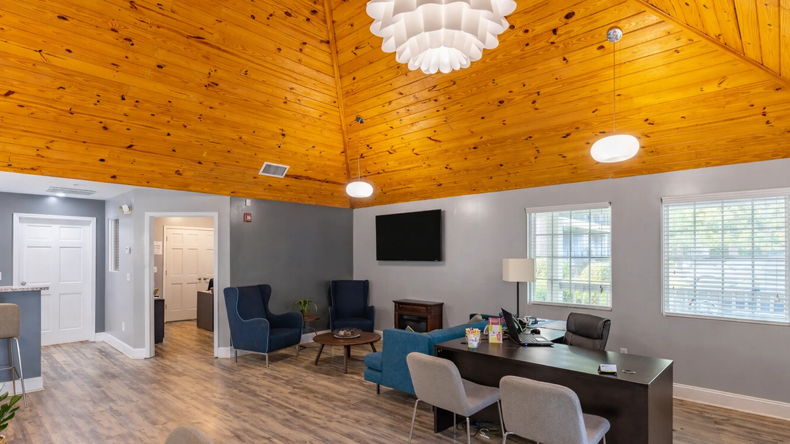 Inviting community office space with modern seating, warm wooden ceiling, and large windows offering natural light.