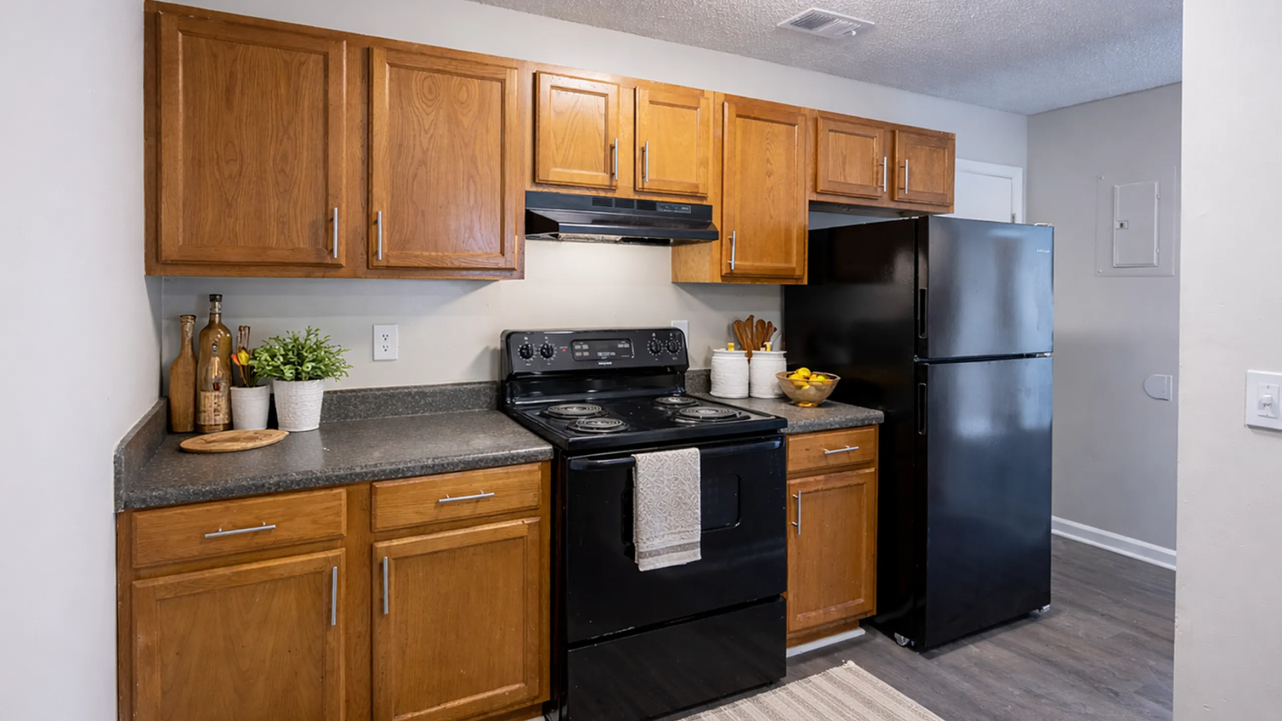 Charming kitchen setup with elegant wooden cabinetry, sleek black appliances, and cozy decorative touches.