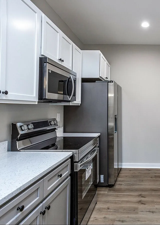 Modern kitchen with sleek white cabinetry, stainless steel appliances, and elegant hardwood flooring.