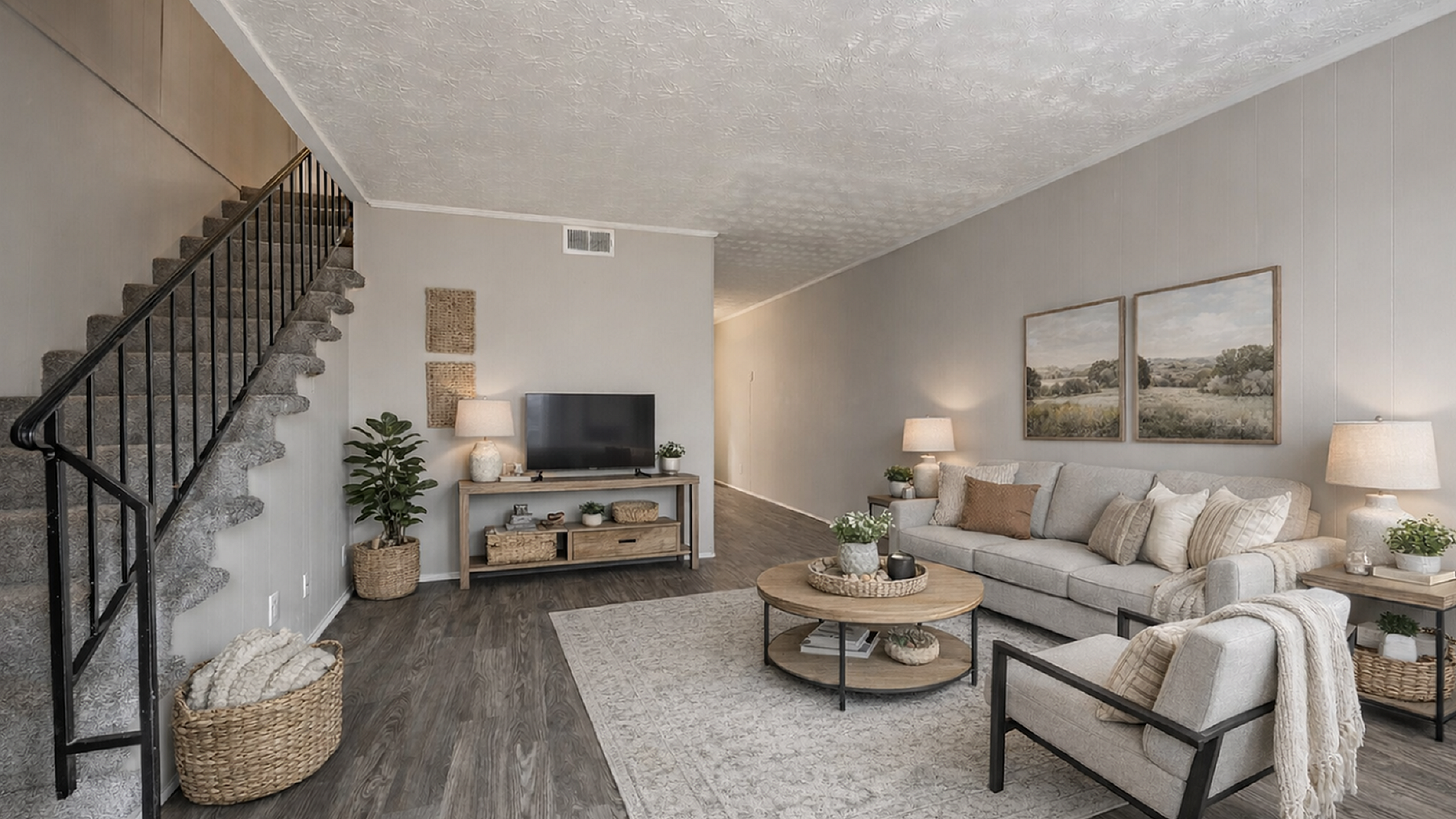 Elegant living room with cozy seating, stylish decor, and inviting natural light, featuring a modern TV setup and chic staircase.