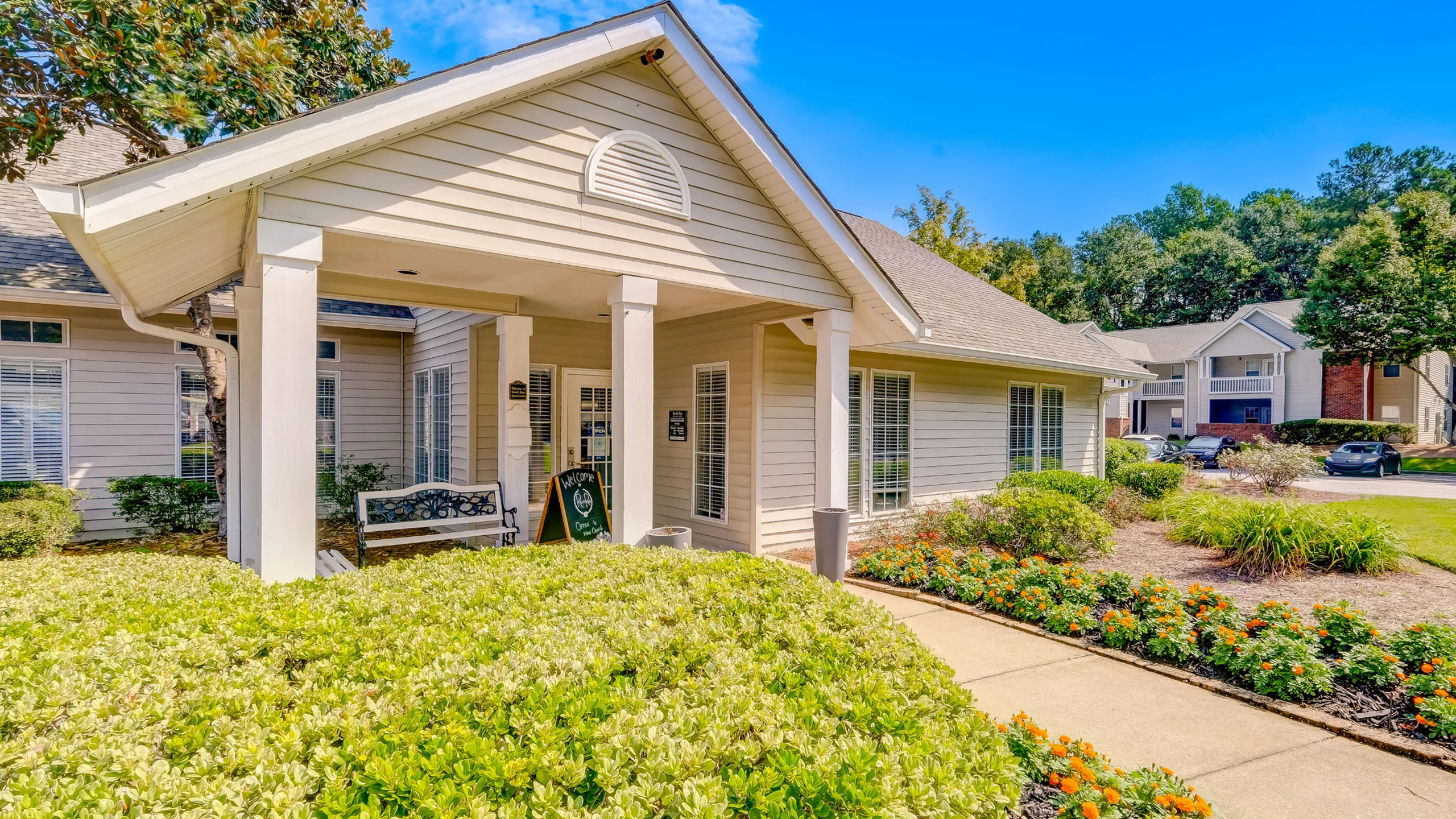 Charming apartment exterior with lush landscaping, inviting entrance, and well-maintained surroundings, perfect for a serene living environment.