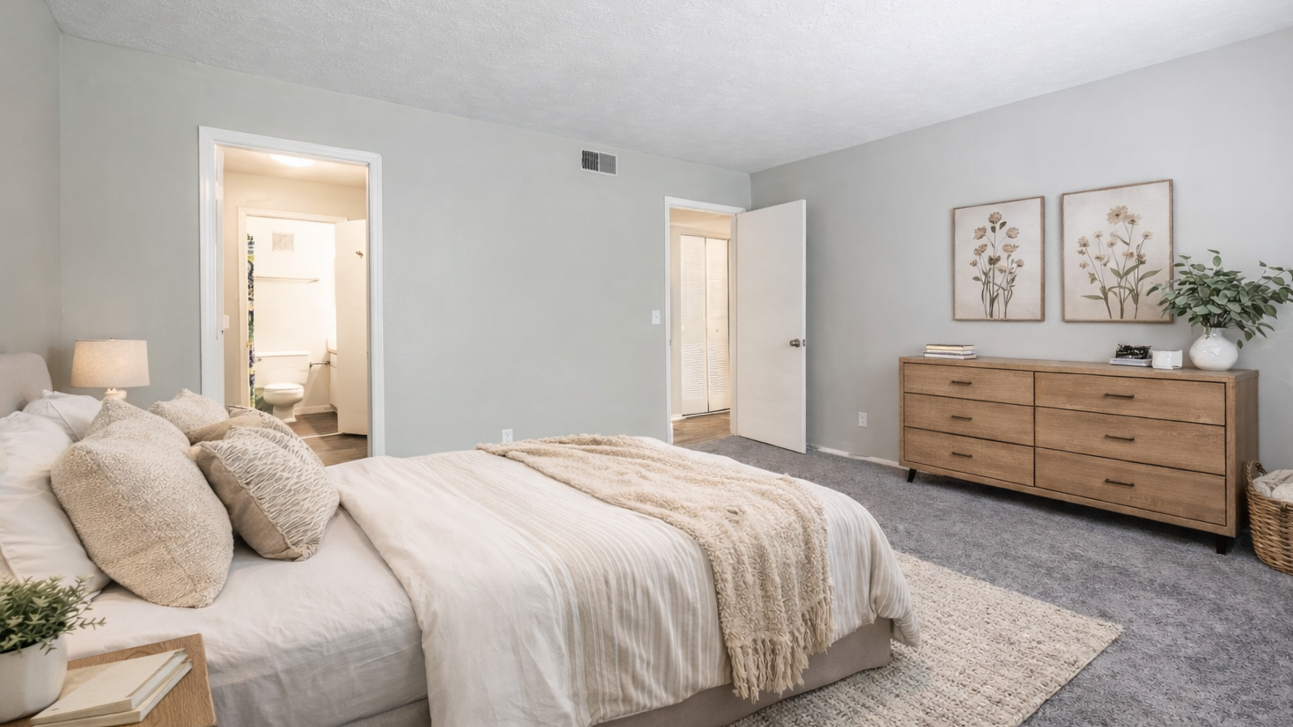 Elegant bedroom with cozy neutral tones, stylish decor, and a wooden dresser creating a serene retreat.