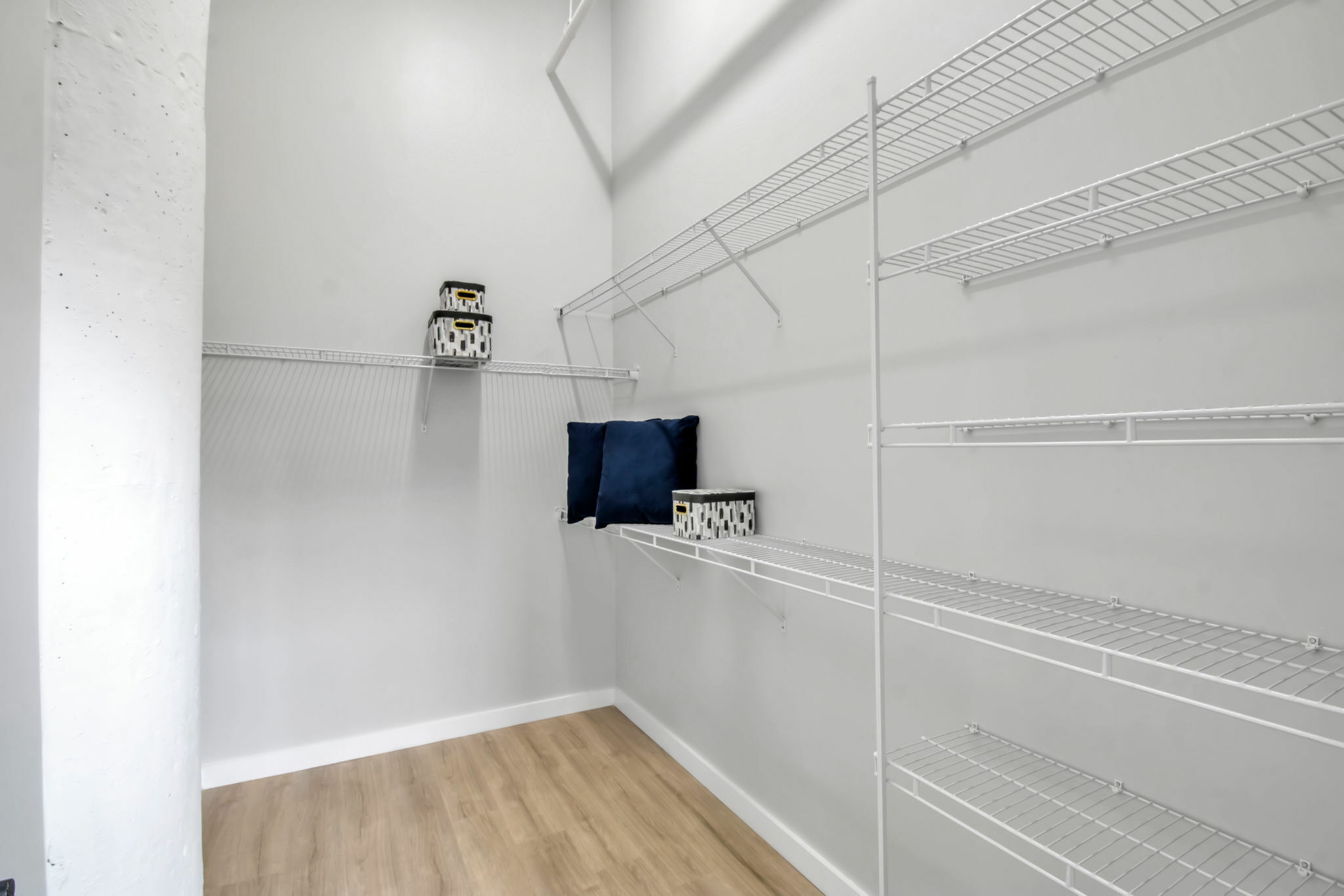 Spacious walk-in closet featuring sleek white wire shelving and modern decor accents, perfect for organized living.