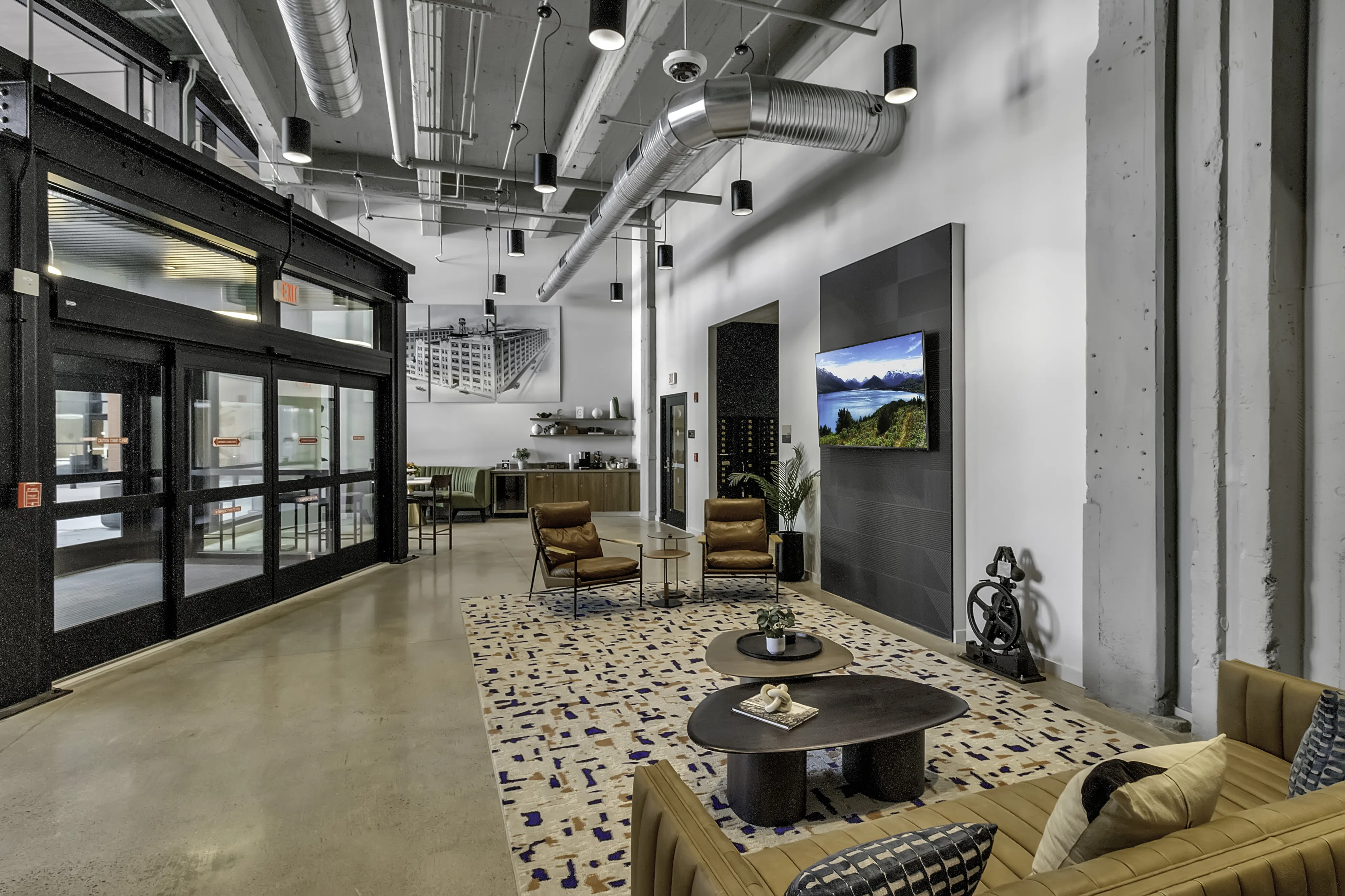 Contemporary industrial-style lobby with high ceilings, modern decor, and comfortable seating, perfect for welcoming guests.