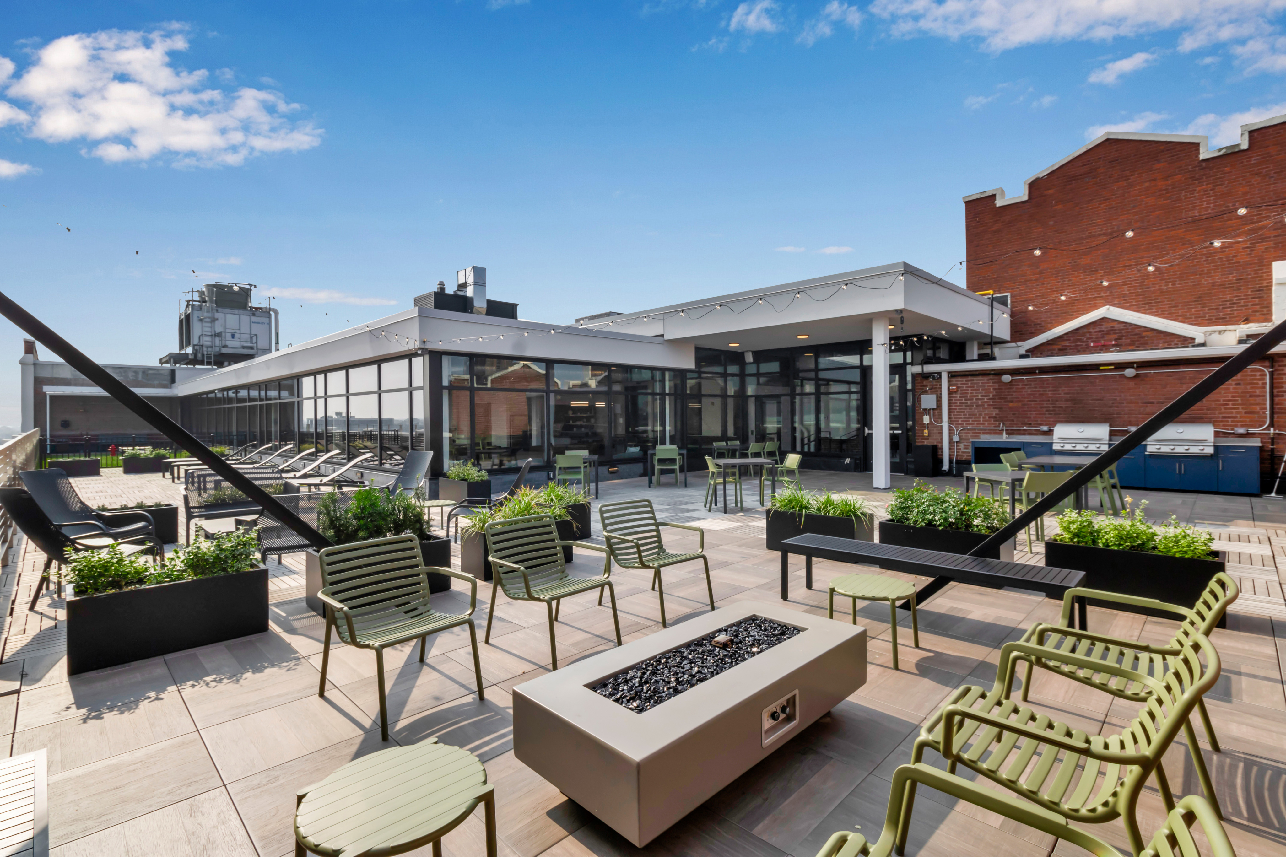 Luxurious rooftop patio featuring stylish seating, sleek fire pit, and modern outdoor kitchen, set against a vibrant cityscape.