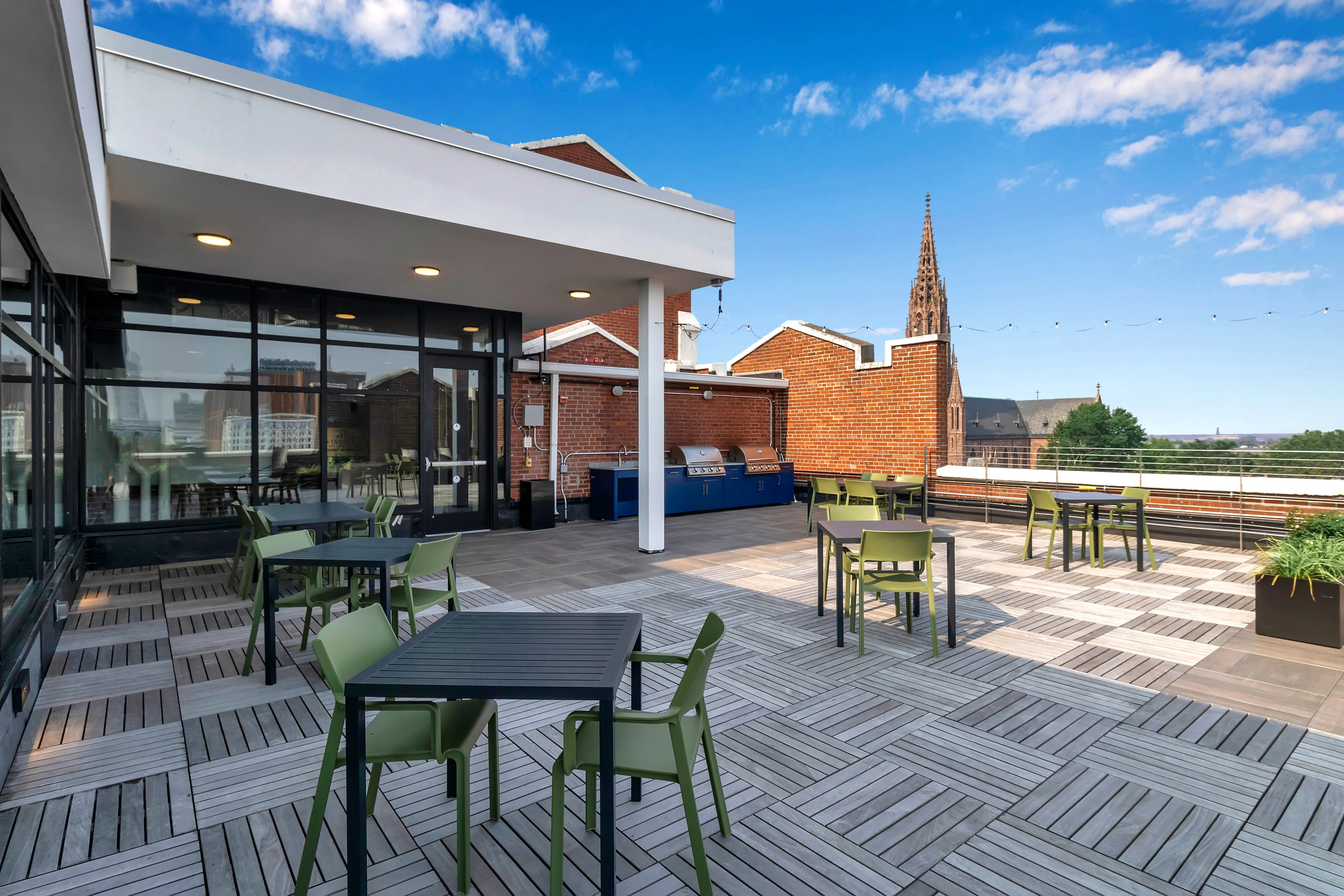 Chic rooftop terrace with modern seating and barbecue grills, offering stunning cityscape views.