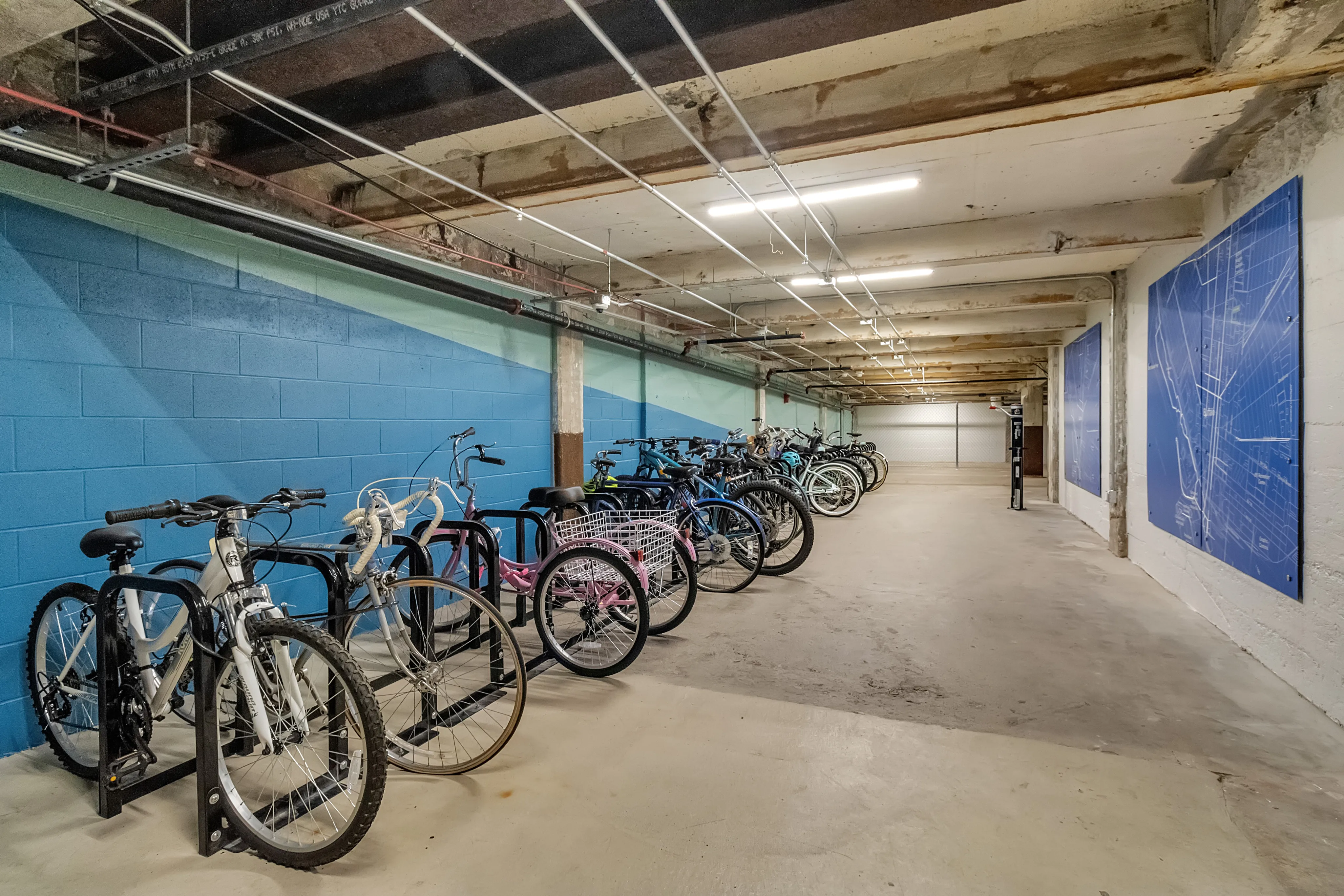 Spacious and secure indoor bicycle storage area with parking racks, vibrant blue wall accents, and ample lighting.