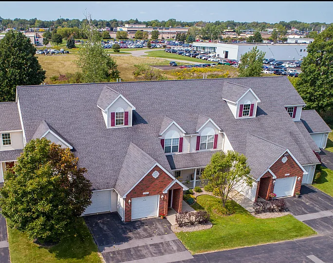 Charming suburban townhome with classic architectural design, lush greenery, and ample parking in a serene neighborhood.