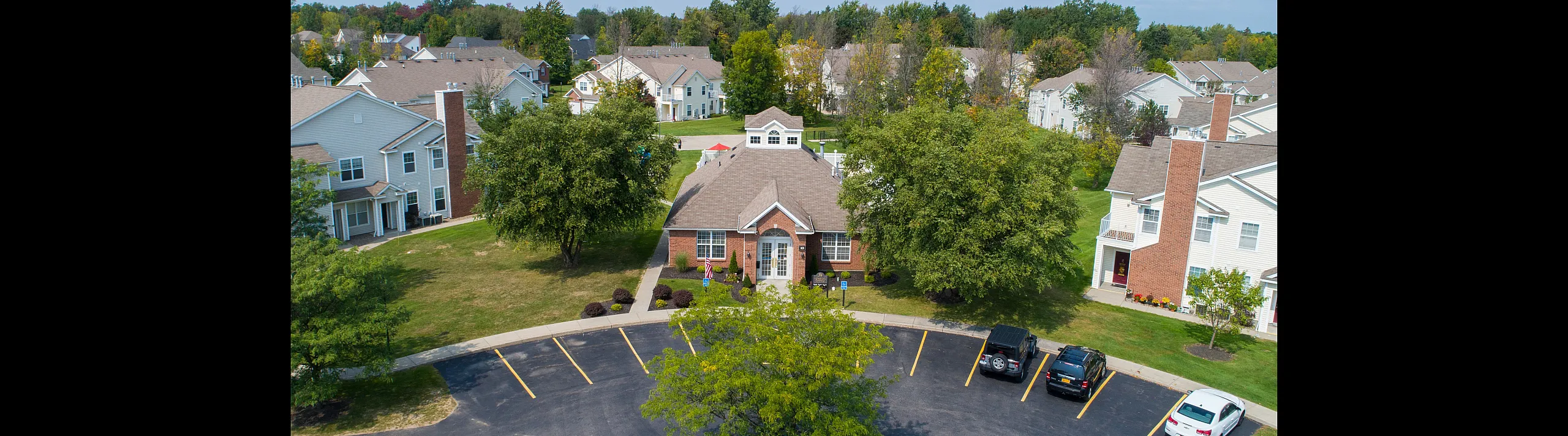 Charming suburban apartment complex with lush greenery, ample parking, and welcoming community vibe.