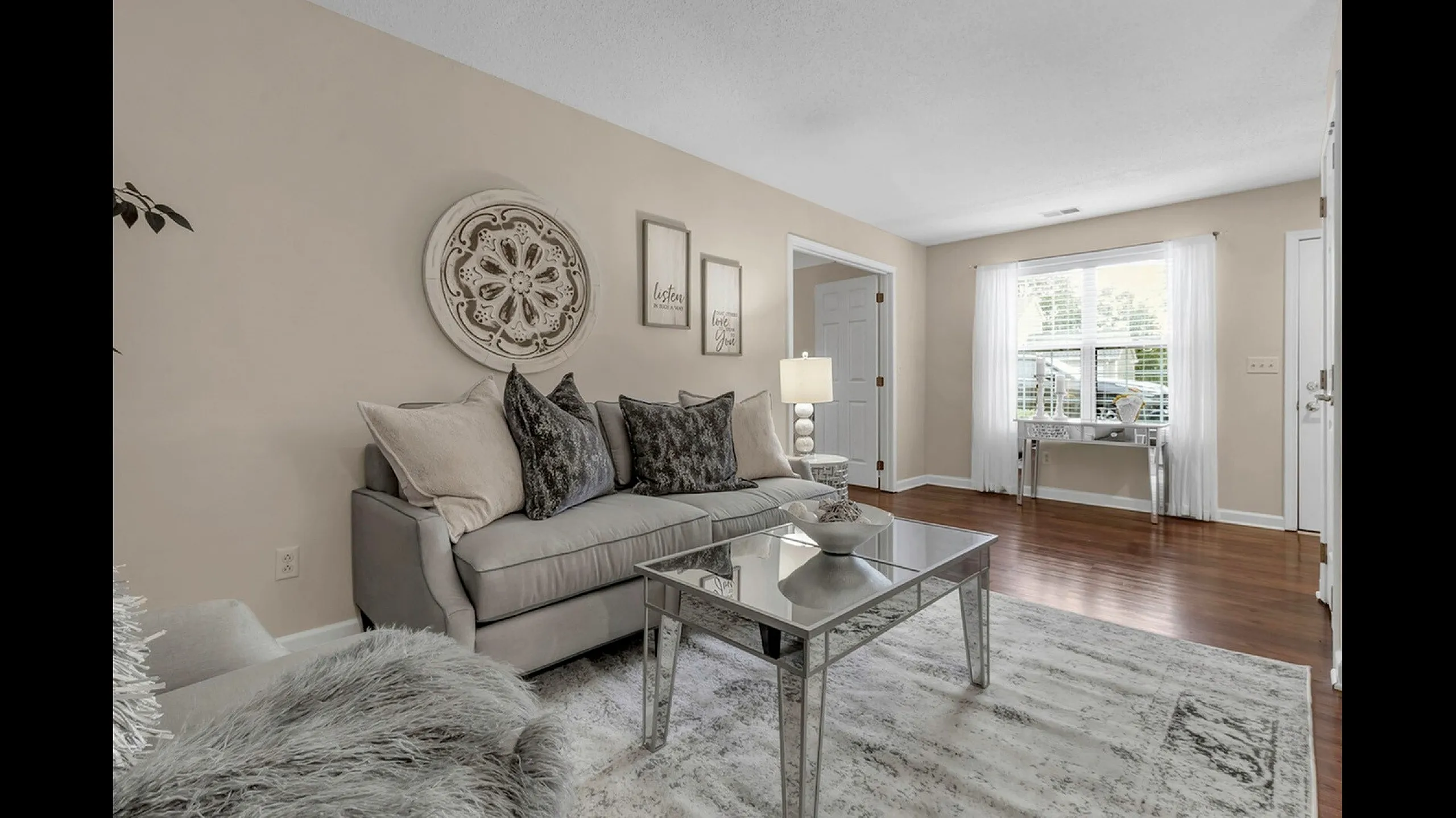 Inviting living room with chic gray sofa, elegant decor, and natural light from large window, creating a cozy atmosphere.