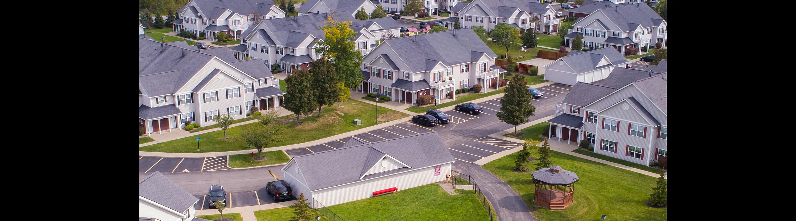 Charming residential community with modern townhouses, lush greenery, scenic pond, and inviting gazebo in a peaceful neighborhood.
