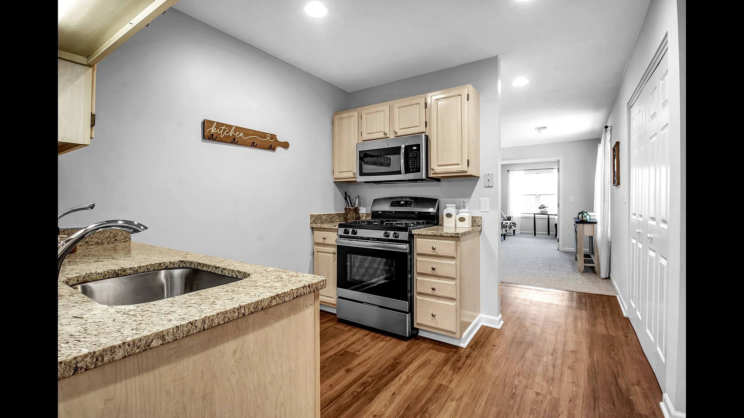 Charming kitchen with modern stainless steel appliances, granite countertops, and open access to a bright living room, perfect for entertaining.