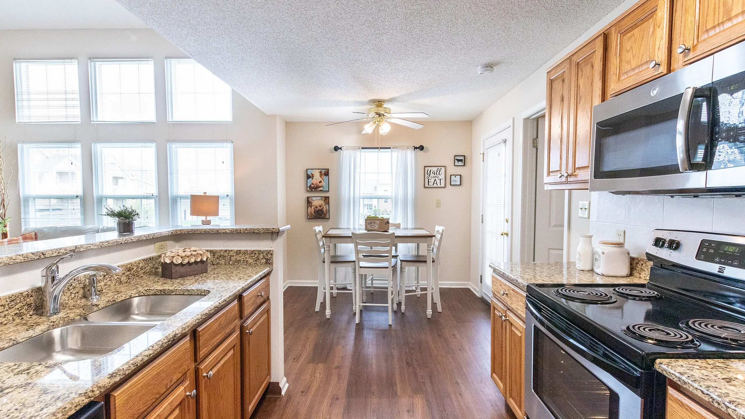 Bright kitchen and dining area with elegant granite countertops, wood cabinetry, and large windows for natural light.