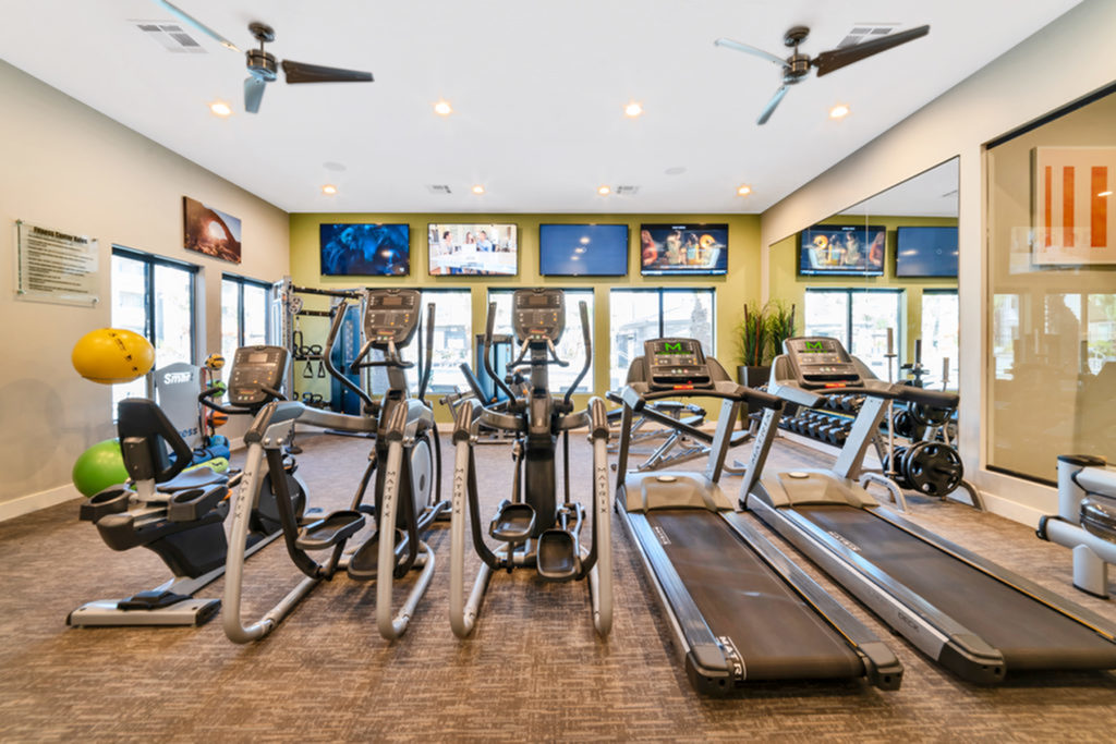Fitness center with treadmills, ellipticals, stair stepper, rower, free weights, exercise balls and bands, and four televisions