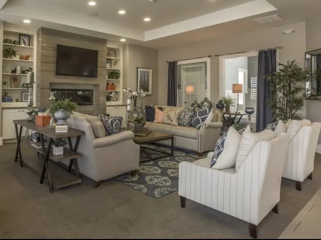 Clubhouse waiting room with 3 couches, 2 chairs, coffee table, flat screen television, and fireplace