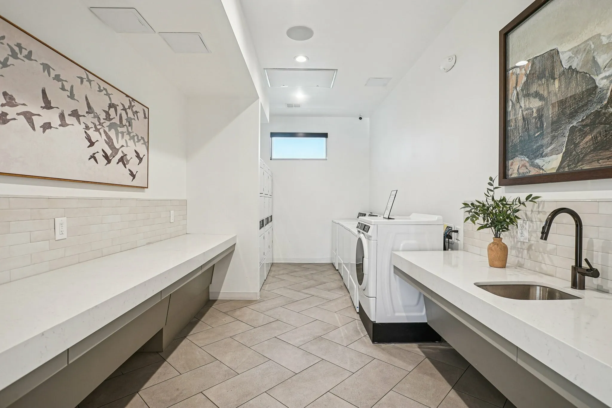 Elegant laundry room with modern appliances, spacious countertops, and stylish artwork creating a serene ambiance.