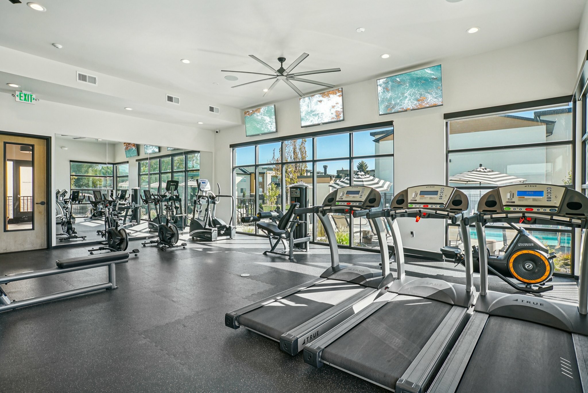 Modern fitness center with state-of-the-art gym equipment, large windows, and bright ambiance, perfect for a refreshing workout experience.