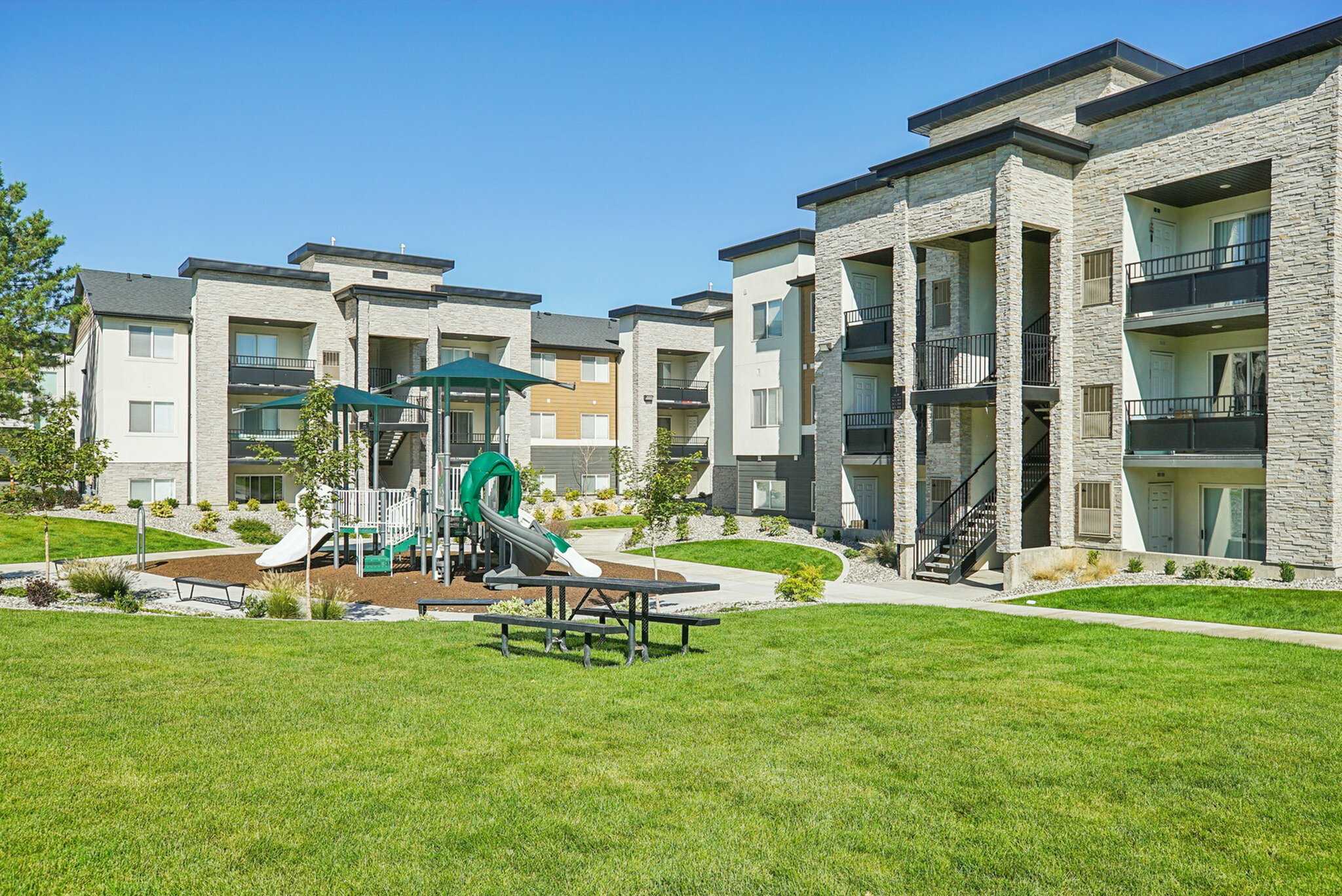 Modern apartment complex with stylish architecture, lush green lawns, and a well-equipped playground for family fun.