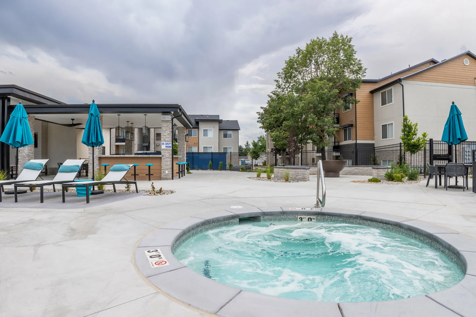 Inviting outdoor space featuring a luxurious hot tub, modern lounge chairs, and shaded patio area.