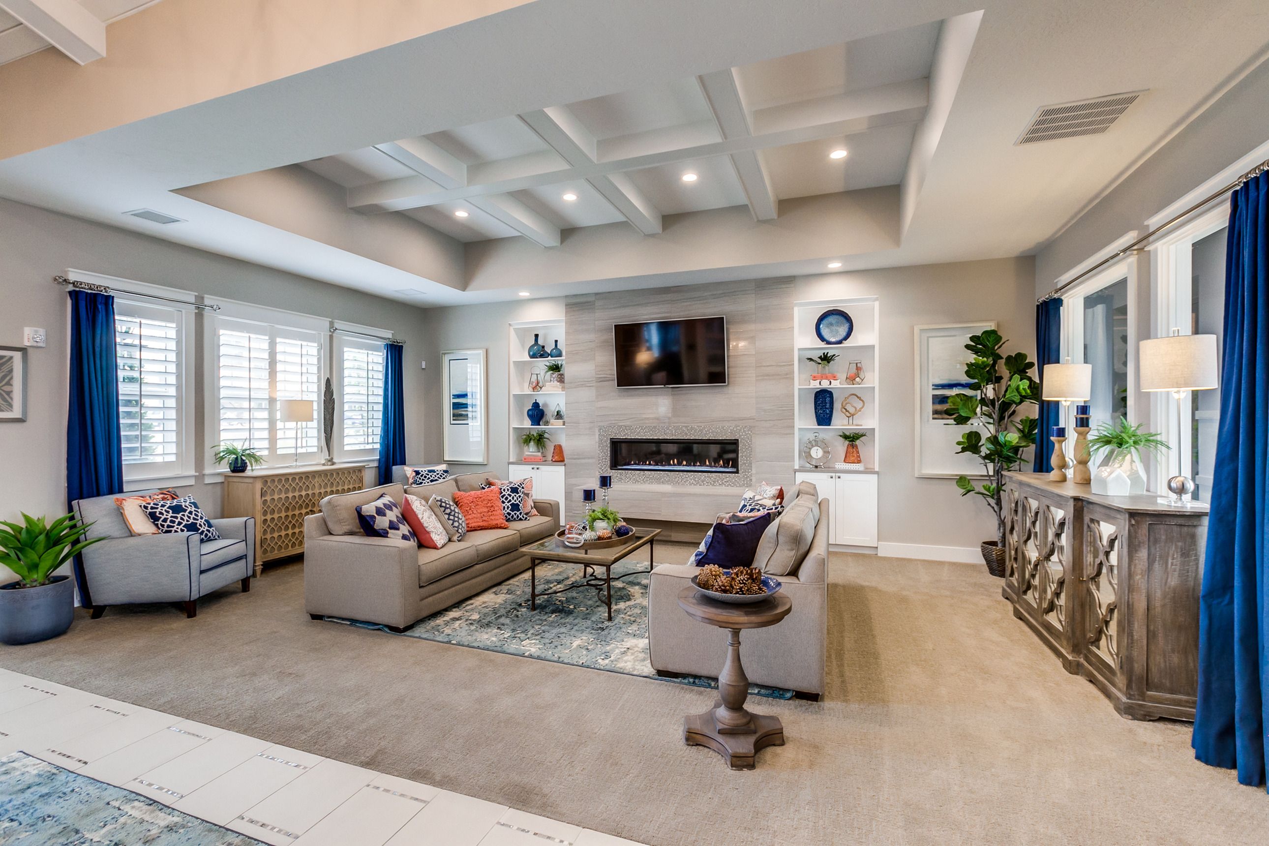 Elegant living room featuring a cozy fireplace, plush seating, and modern decor with vibrant blue accents and abundant natural light.