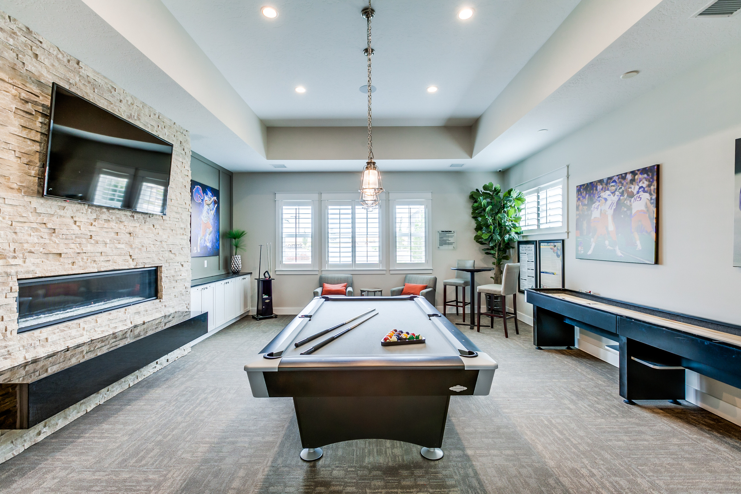 Modern entertainment lounge featuring a sleek pool table, cozy seating area, and contemporary fireplace with stylish decor.
