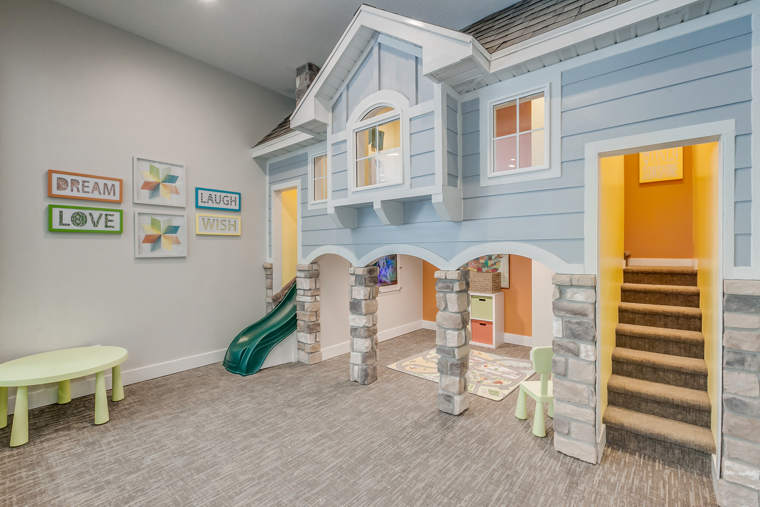 Charming playhouse room with a blue cottage design, indoor slide, and playful decor, perfect for imaginative fun.
