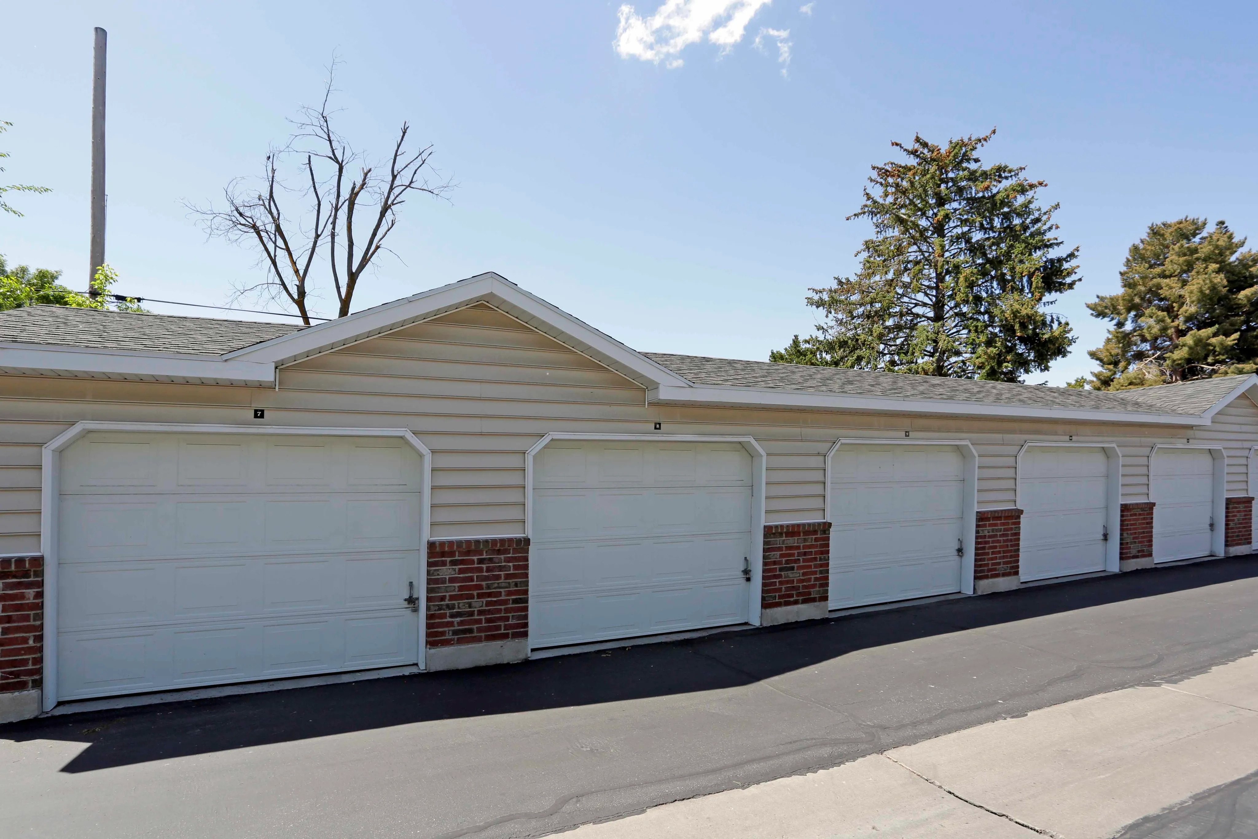 Modern multi-car garage with sleek white doors, set against a well-maintained exterior and bright blue sky.