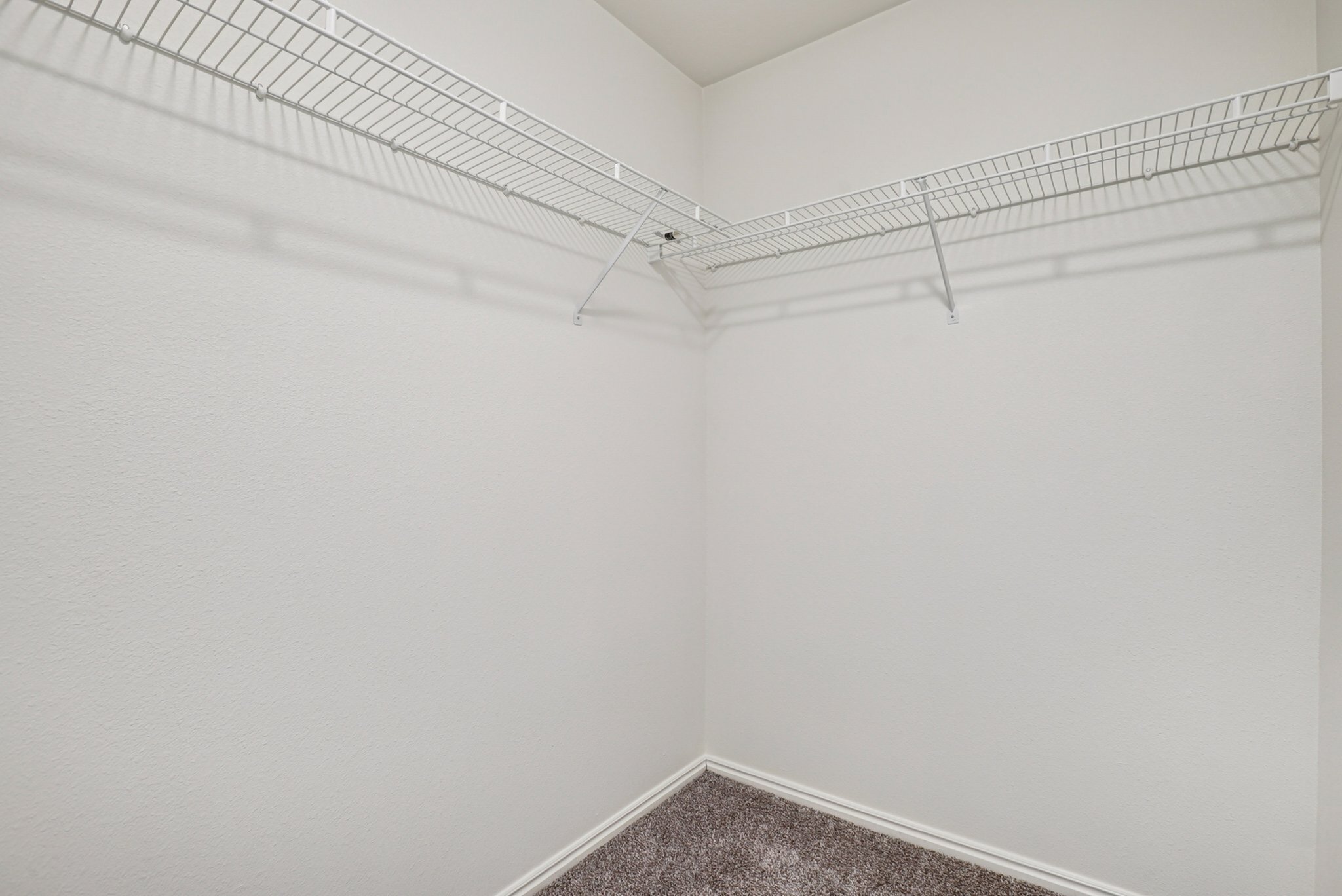 Spacious, modern closet with sleek wire shelving, perfect for maximizing storage in a vibrant apartment setting.