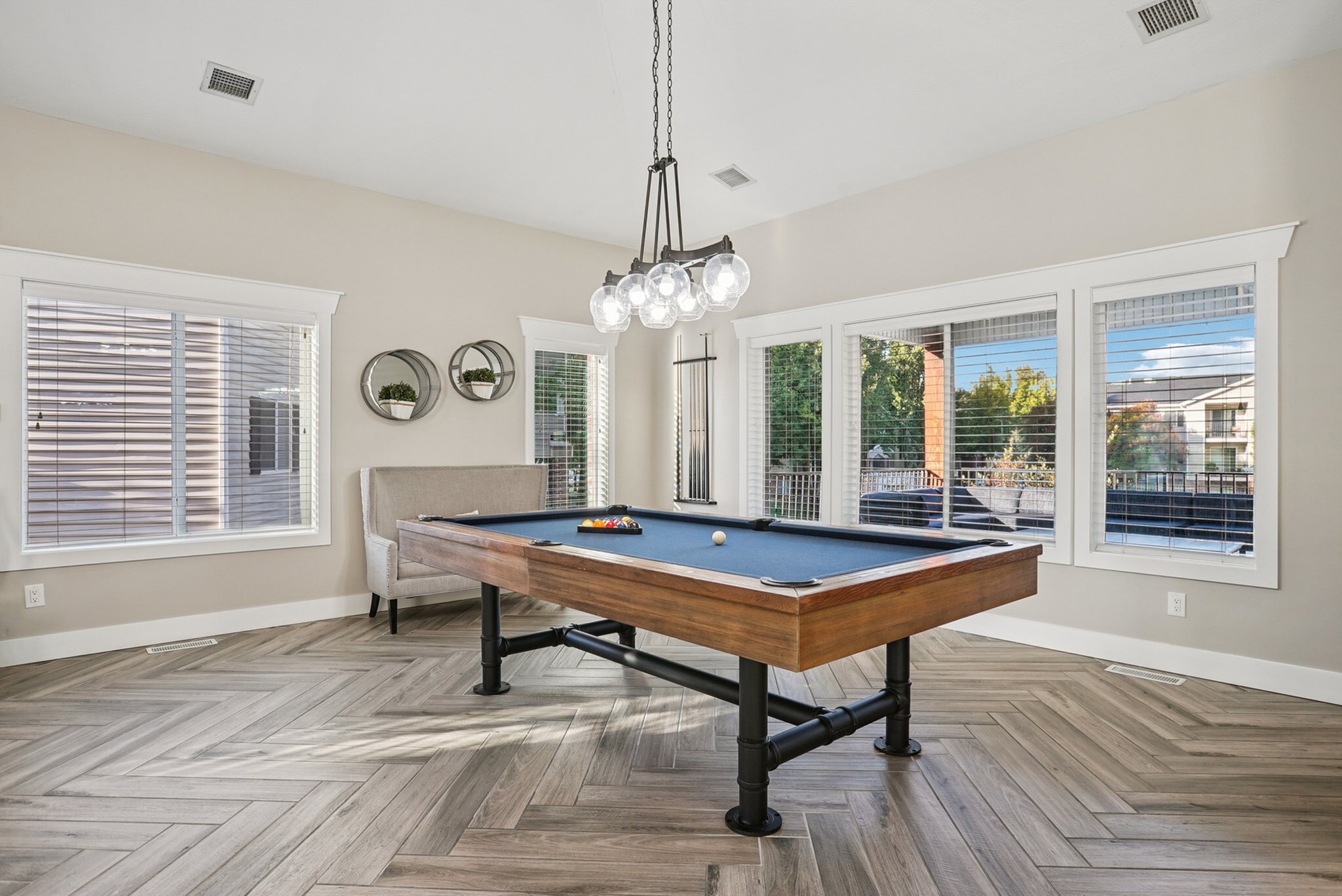 Elegant leisure room featuring a stylish billiard table, modern chandelier, and large windows with scenic views.