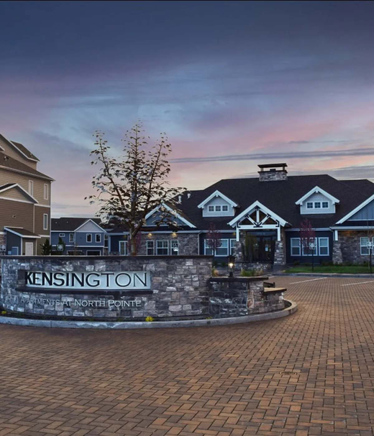 Elegant apartment building at Kensington North Pointe, featuring modern architecture with a scenic sunset backdrop.