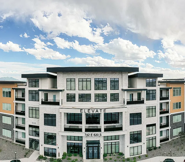 Contemporary apartment building with modern architecture, large windows, and beautiful mountain views.